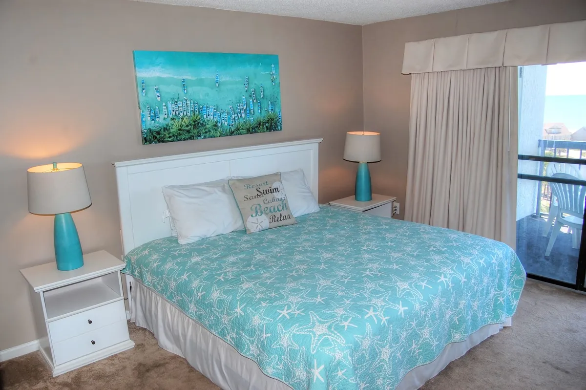 A serene bedroom featuring a bed with a starfish-patterned blanket, complemented by ocean-themed artwork and matching nightstands with lamps. The tranquil setting is suffused with soft, natural light, creating an inviting atmosphere ideal for rest and relaxation.