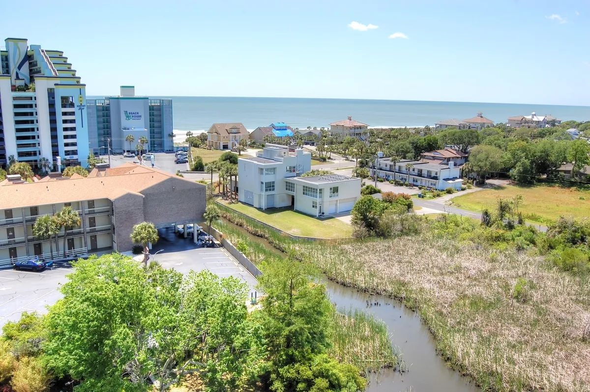 A wide panorama captures the coastline with sweeping ocean views, modern architecture, and lush greenery bordering marshland. The image conveys the expansive beauty and varied landscapes of Myrtle Beach's Golden Mile, inviting exploration and relaxation in equal measure.